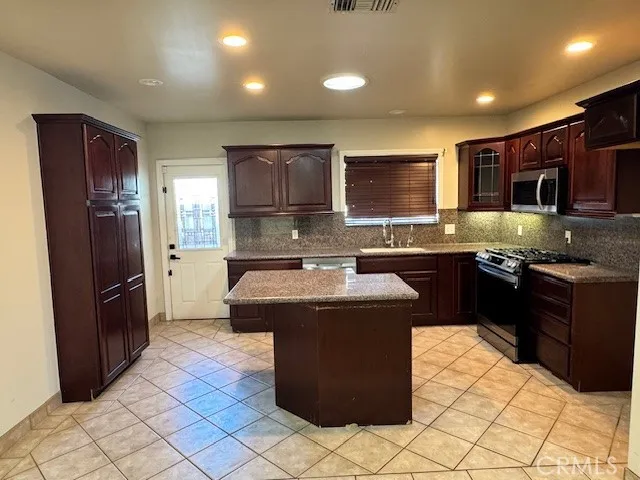 a kitchen with stainless steel appliances granite countertop a stove a sink dishwasher a refrigerator and a microwave