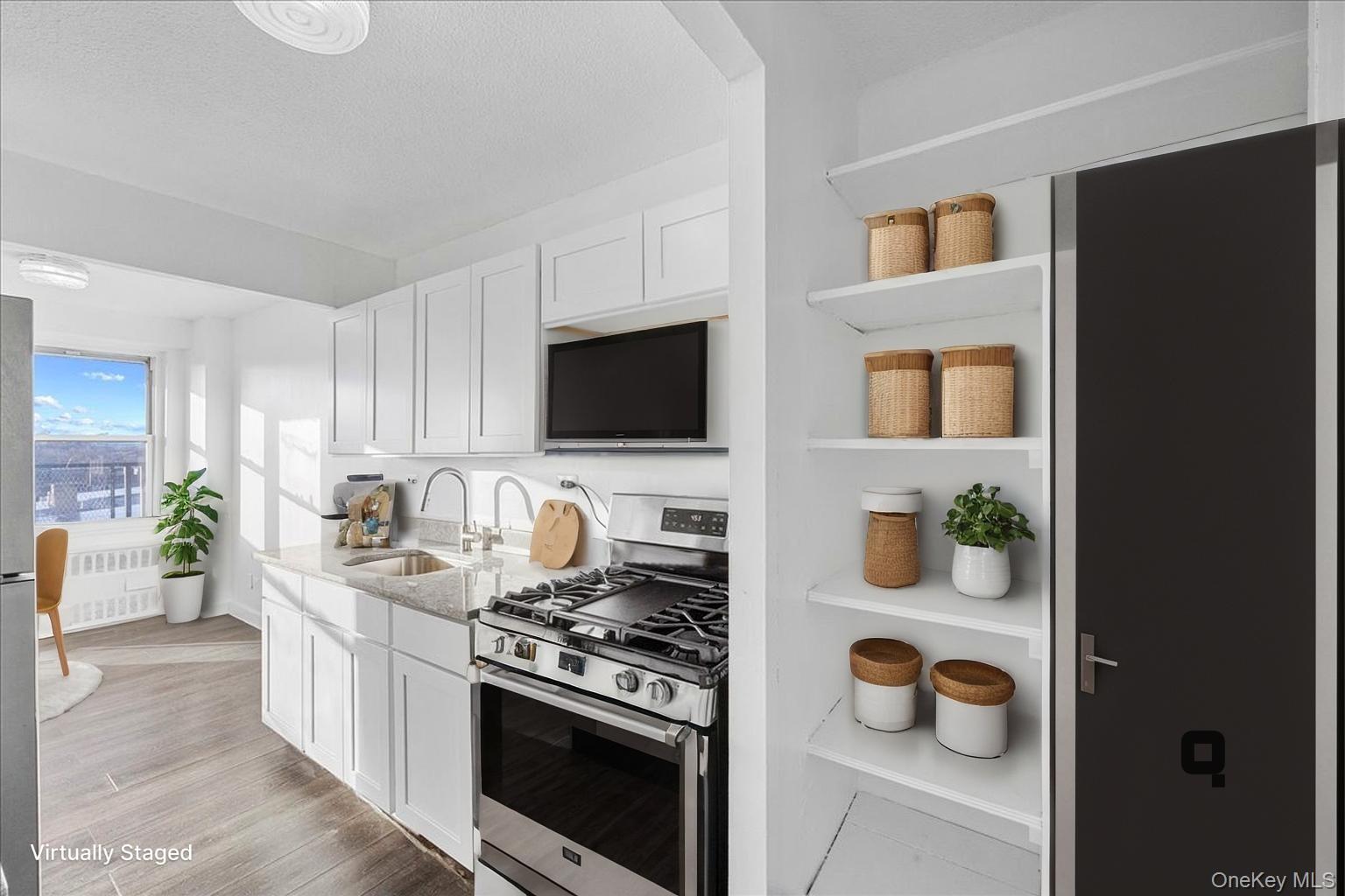 Virtually Staged Kitchen featuring appliances with stainless steel finishes, white cabinets, light stone countertops, open shelves, and light wood-type flooring