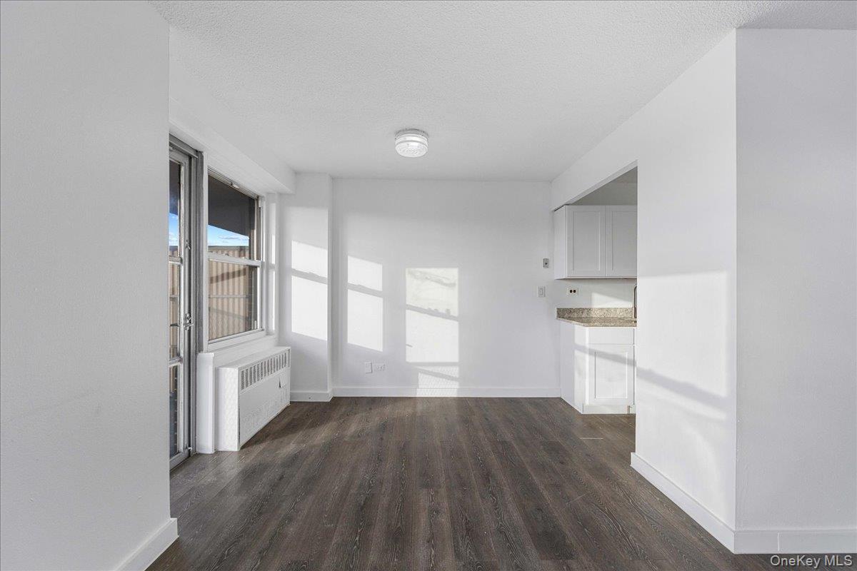 2550 Olinville Avenue, Unit 8H Bronx, NY 10467 - Photo 11 of 24 Corridor with dark wood-style floors, radiator, and a textured ceiling