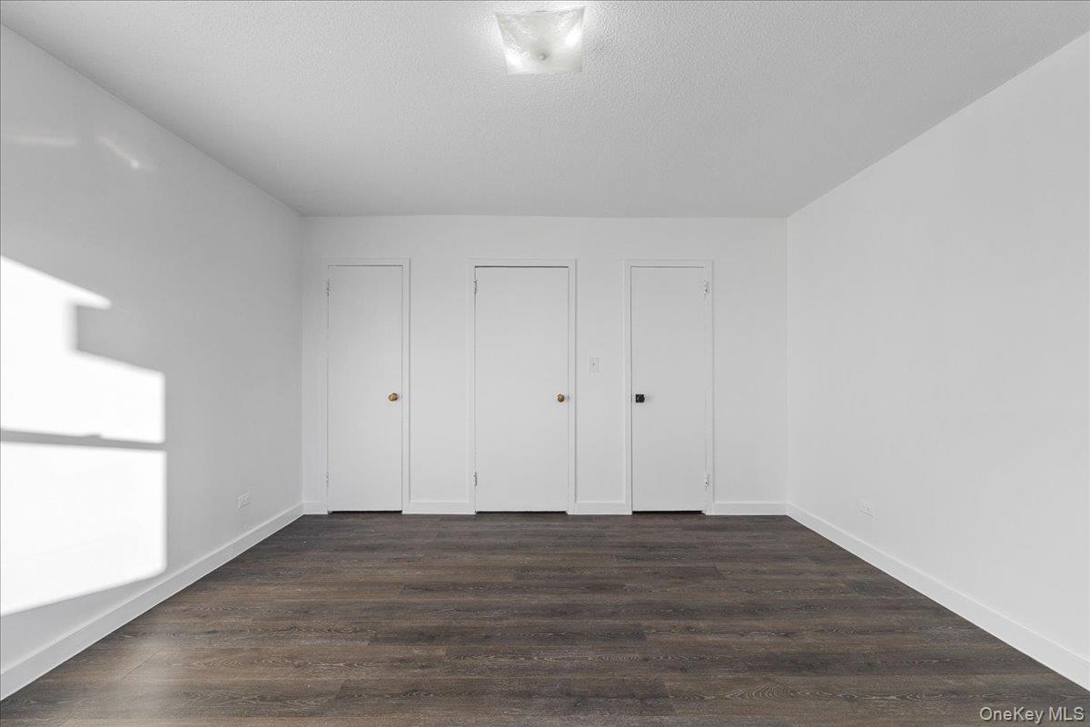 2550 Olinville Avenue, Unit 8H Bronx, NY 10467 - Photo 16 of 24 Unfurnished bedroom featuring dark wood finished floors and multiple closets