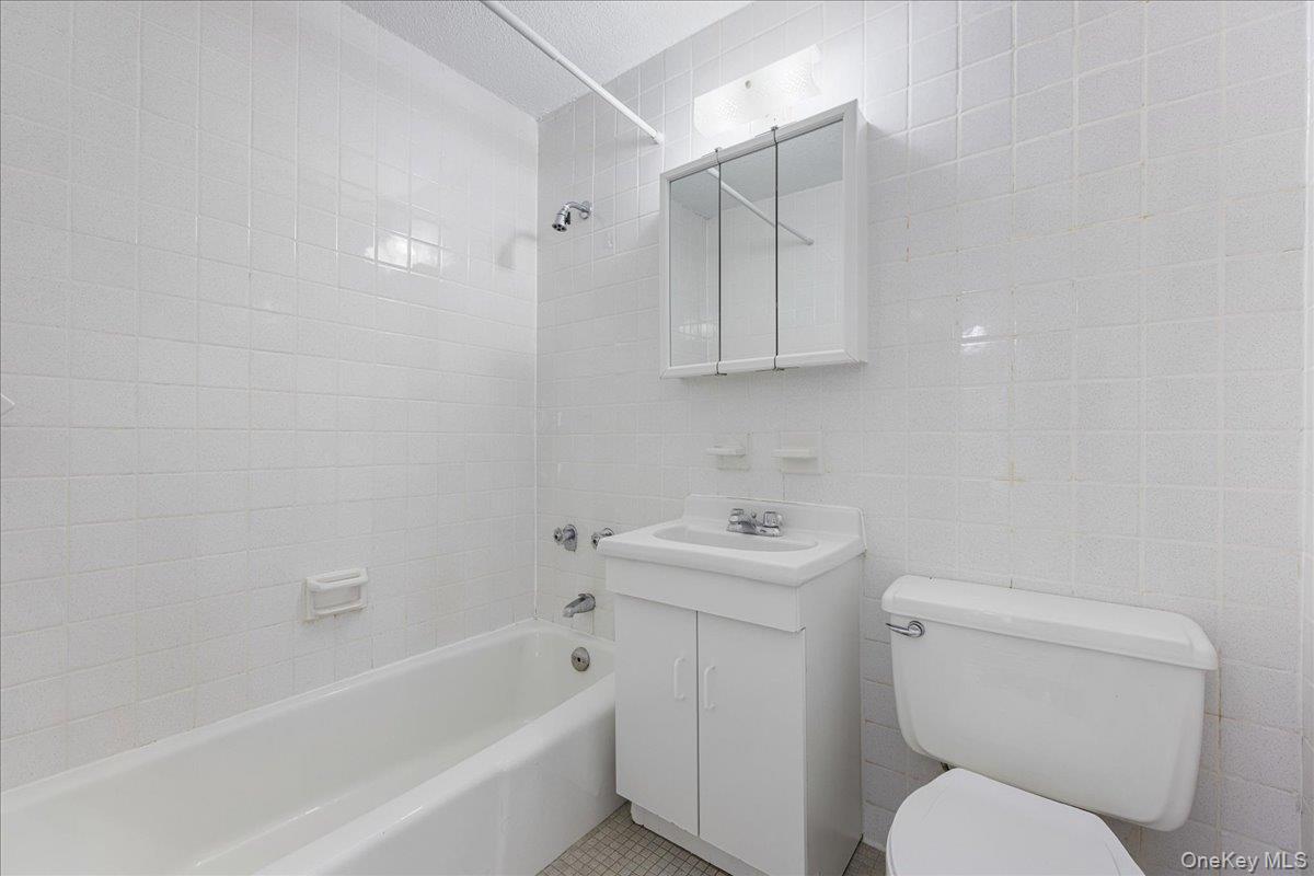 2550 Olinville Avenue, Unit 8H Bronx, NY 10467 - Photo 18 of 24 Full bath with vanity, tile walls, and shower / bathtub combination