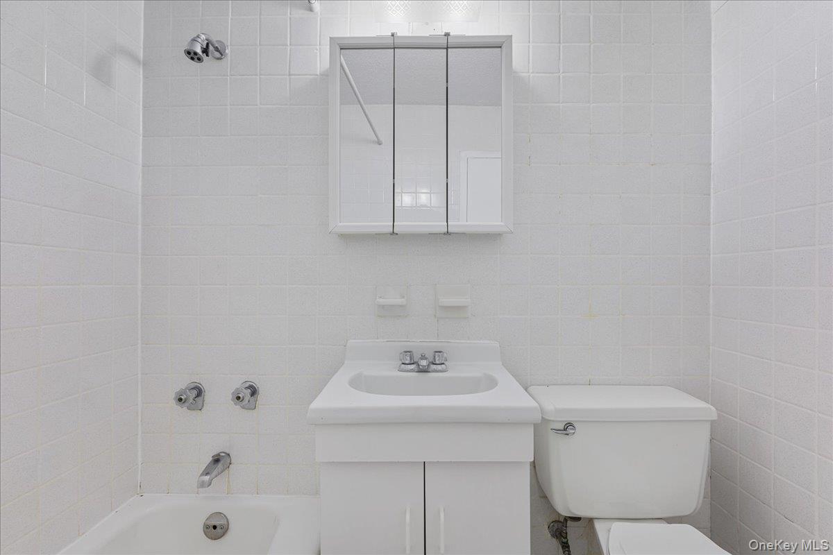 2550 Olinville Avenue, Unit 8H Bronx, NY 10467 - Photo 19 of 24 Full bath featuring vanity, tub / shower combination, and tile walls