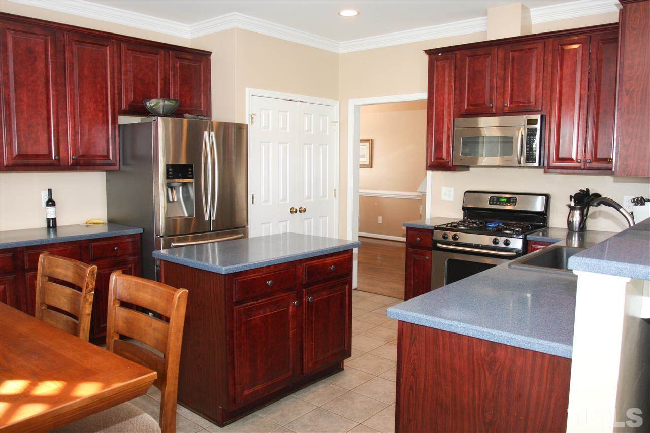 197 Mickleson Ridge Drive Raleigh, NC 27603 - Photo 5 of 25 a kitchen with stainless steel appliances granite countertop a stove a refrigerator and a wooden cabinets