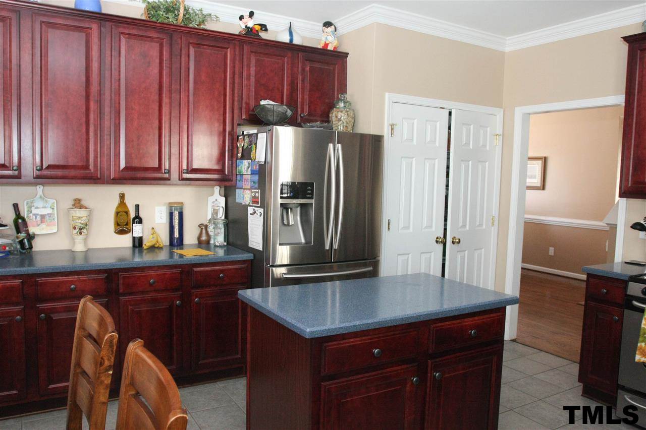 197 Mickleson Ridge Drive Raleigh, NC 27603 - Photo 7 of 25 a kitchen with stainless steel appliances granite countertop a refrigerator a sink and wooden cabinets