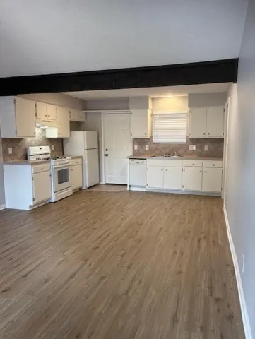 a large kitchen with a wooden floor and cabinets