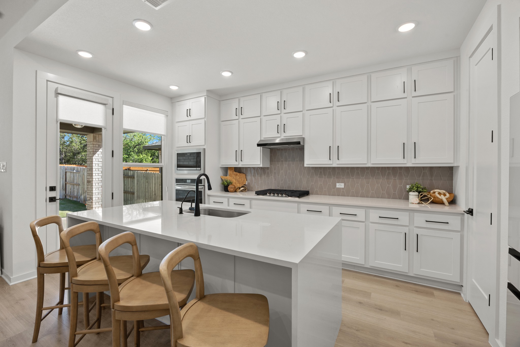 6000 Sean Paul Lane Georgetown, TX 78628 - Photo 11 of 35 Kitchen with white cabinets, light wood finished floors, a breakfast bar, light stone counters, and recessed lighting