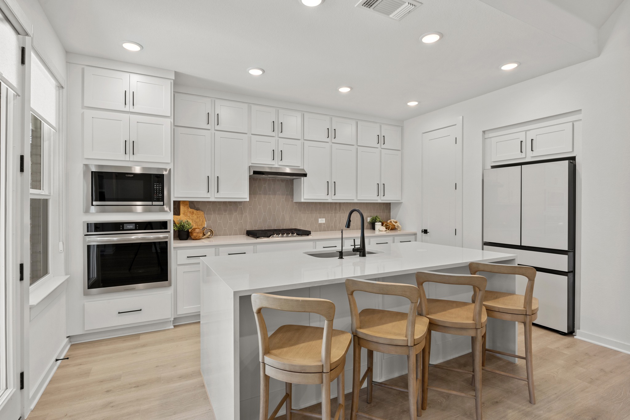 6000 Sean Paul Lane Georgetown, TX 78628 - Photo 10 of 35 Kitchen with stainless steel appliances, a breakfast bar area, white cabinets, decorative backsplash, and light wood-style floors