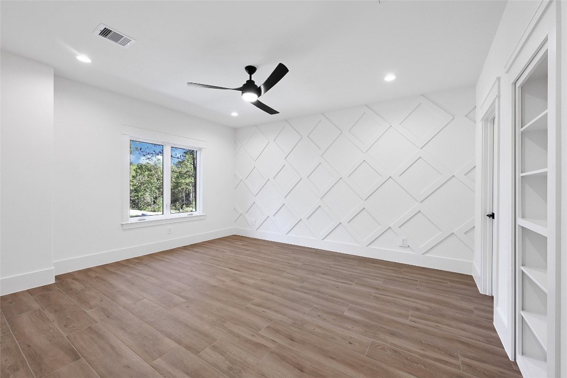 7244 Red Oak Grove Road Montgomery, TX 77316 - Photo 32 of 49 an empty room with wooden floor chandelier fan and windows