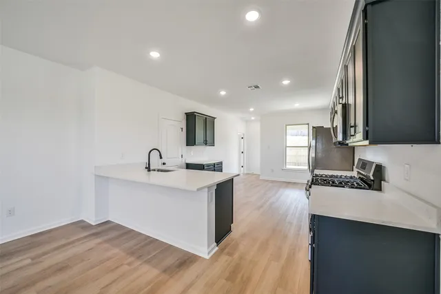 a kitchen with stainless steel appliances a sink stove and cabinets