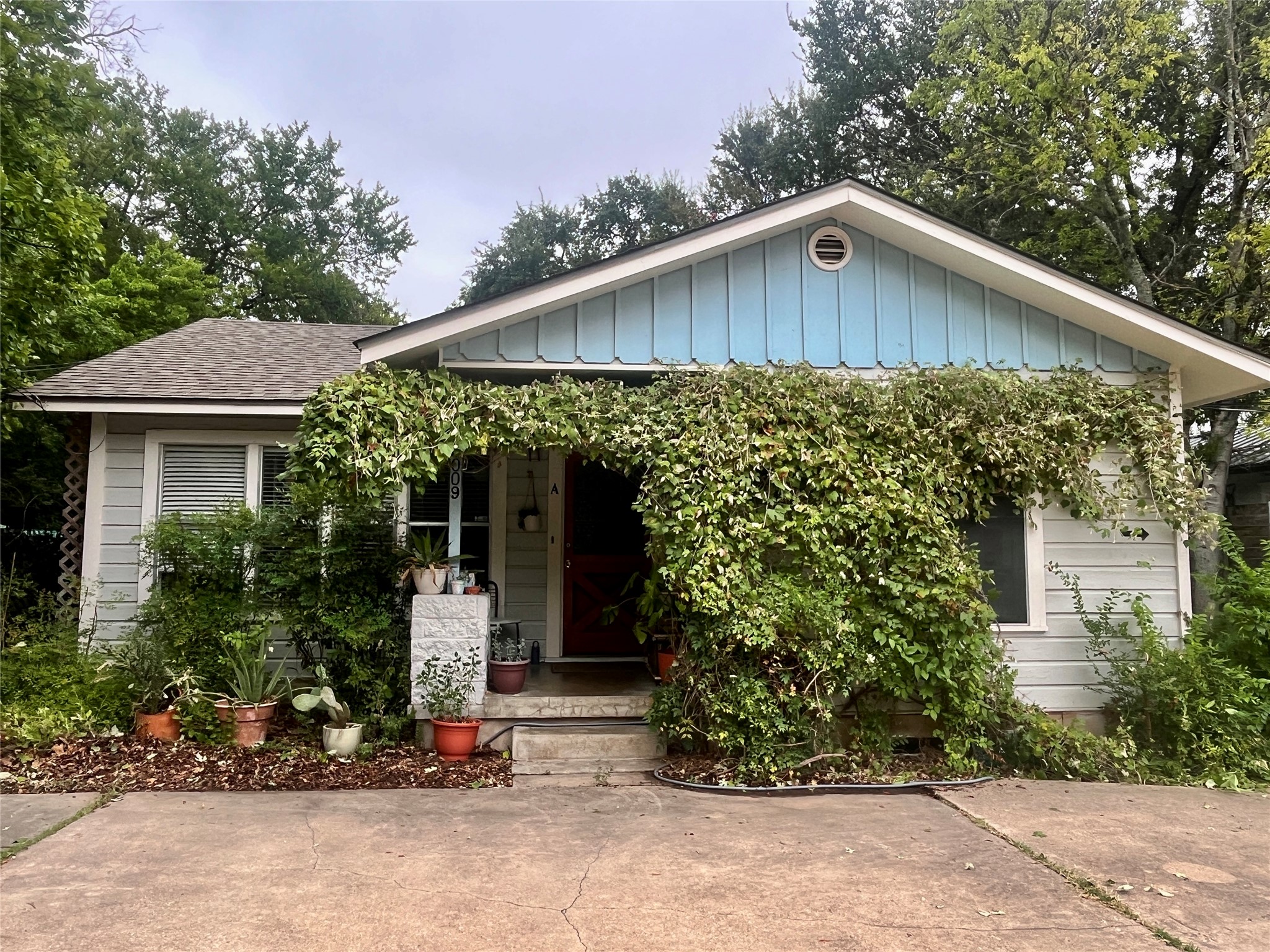 3009 Cherrywood Road, Unit A Austin, TX 78722 - Photo 1 of 13 A charming single-story residence with light blue siding and a welcoming front porch draped in lush greenery.