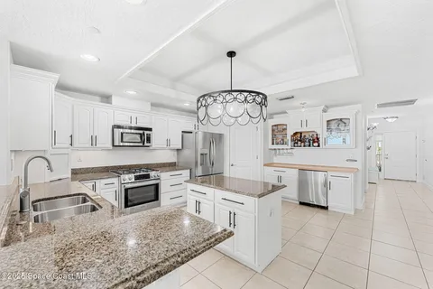 a kitchen with stainless steel appliances granite countertop a stove a sink dishwasher a refrigerator and white cabinets with wooden floor