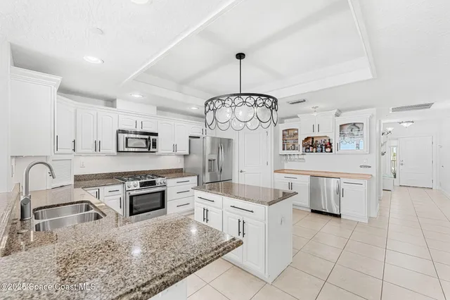 a kitchen with stainless steel appliances granite countertop a stove a sink dishwasher a refrigerator and white cabinets with wooden floor