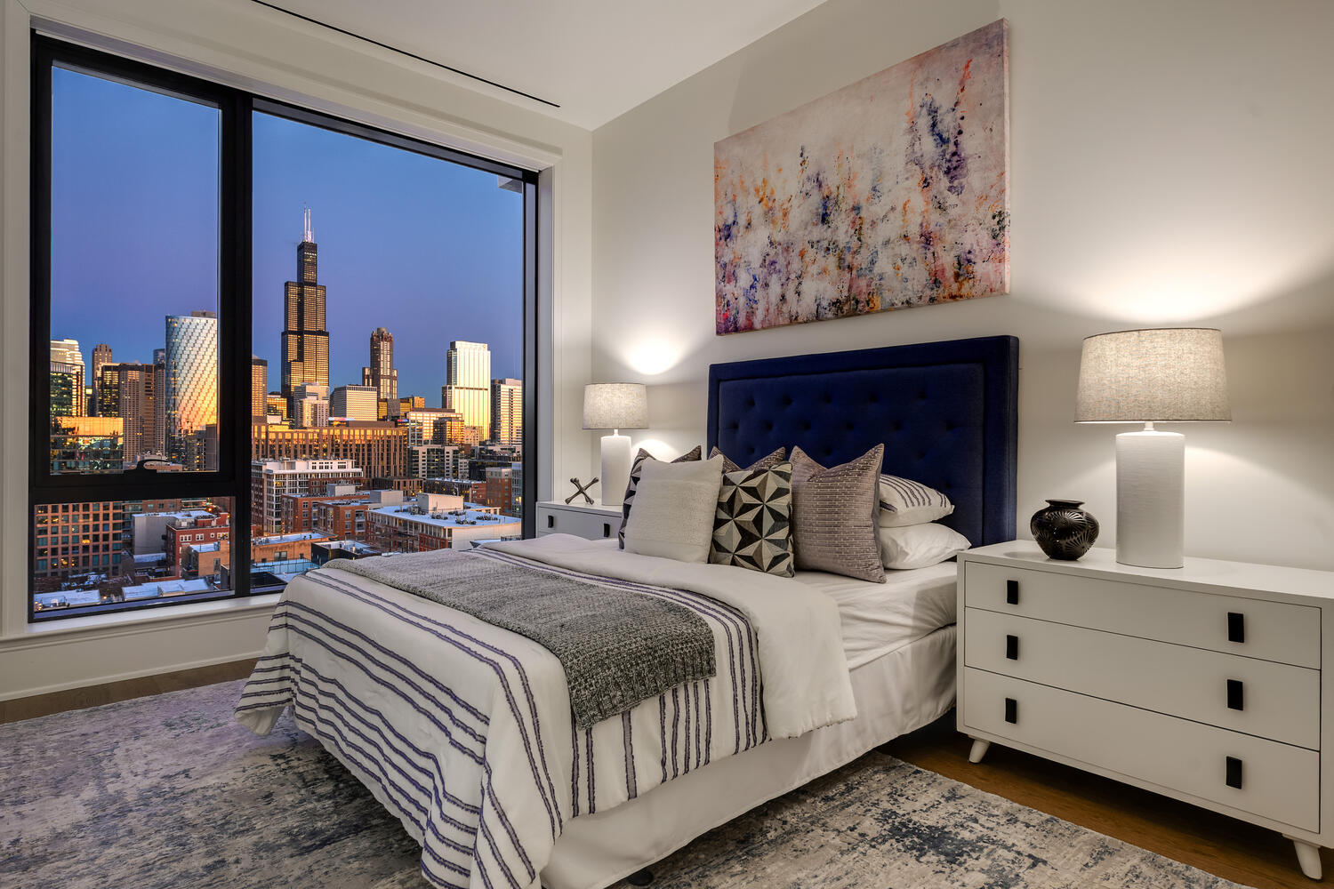 21 North May Street, Unit 1301 Chicago, IL 60607 - Photo 30 of 44 a bedroom with a large bed and a lamp on dresser