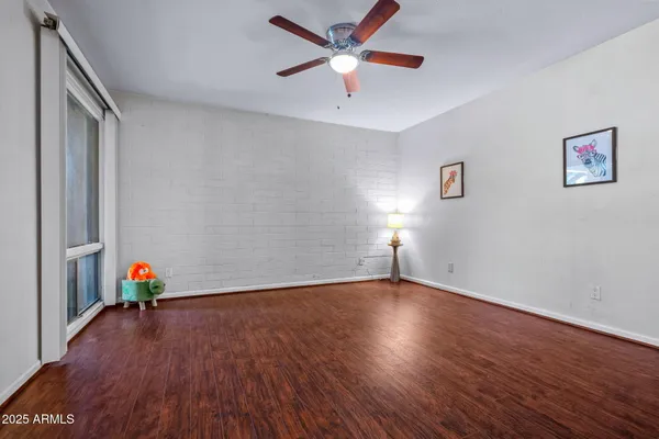 an empty room with wooden floor and a ceiling fan