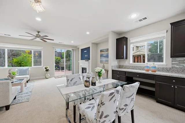 a kitchen with stainless steel appliances kitchen island granite countertop a stove a sink a refrigerator a dining table and chairs