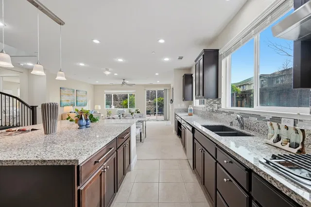 a kitchen with kitchen island granite countertop a stove a sink a microwave a refrigerator and cabinets