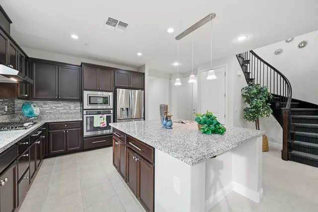 a kitchen with stainless steel appliances granite countertop kitchen island wooden cabinets and refrigerator
