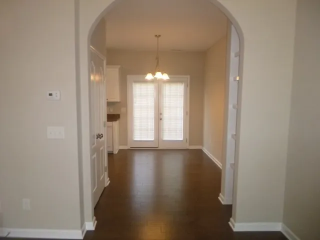 a view of a hallway with wooden floor and chandelier