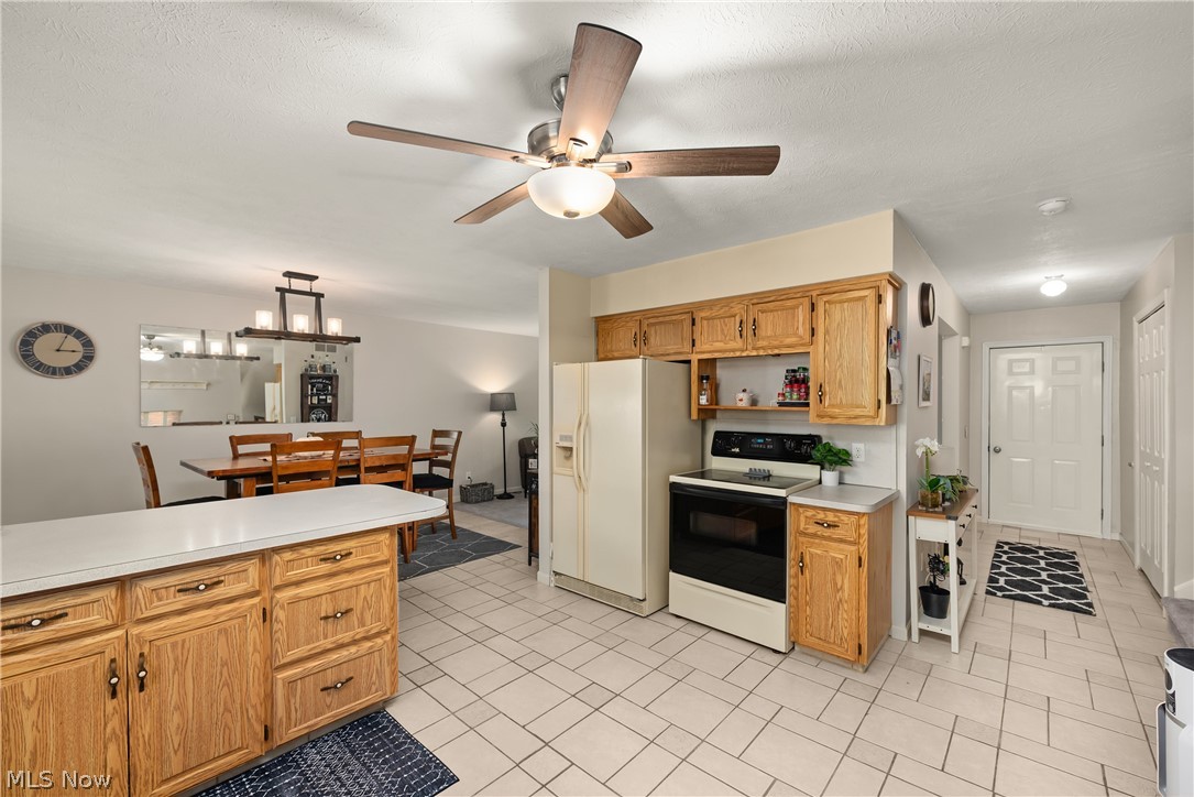 75 Houghton Road Northfield, OH 44067 - Photo 12 of 48 Spacious kitchen featuring wood cabinetry, tile flooring, stainless steel appliances including a refrigerator and electric range, and ample counter space with an island