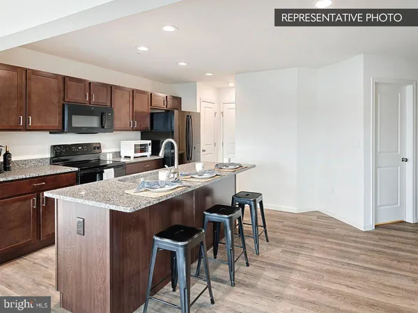 a kitchen with stainless steel appliances granite countertop a sink a stove a refrigerator cabinets and a dining table