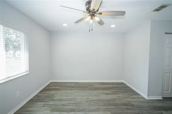 a view of an empty room with wooden floor and a window