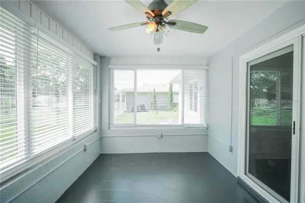 a view of an empty room with window and a kitchen view