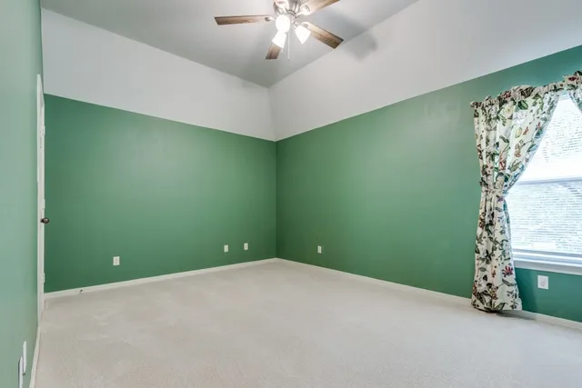 an empty room with a chandelier fan and windows
