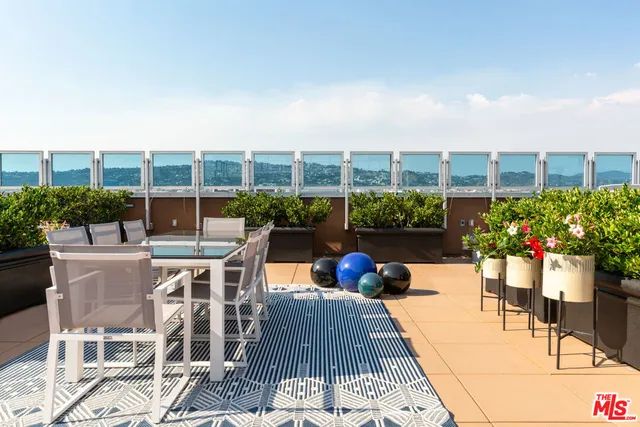 a view of a patio with a dining table and chairs with plants