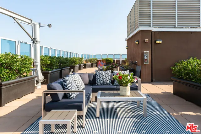 a view of a patio with couches chairs potted plants and wooden floor
