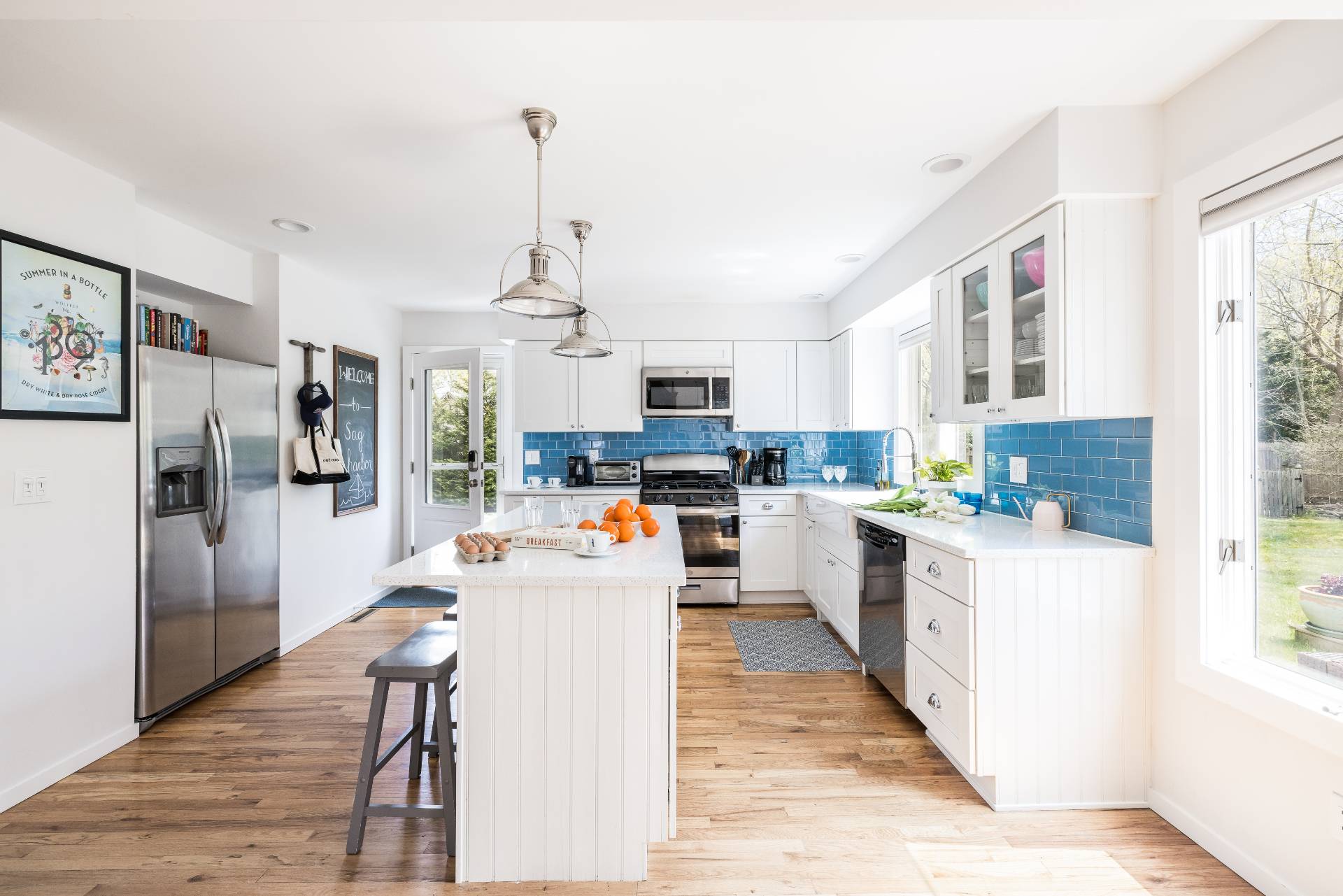 4594 Noyack Road Sag Harbor, NY 11963 - Photo 14 of 31 a kitchen view with stainless steel appliances kitchen island granite countertop a refrigerator a stove a sink dishwasher and white cabinets with wooden floor