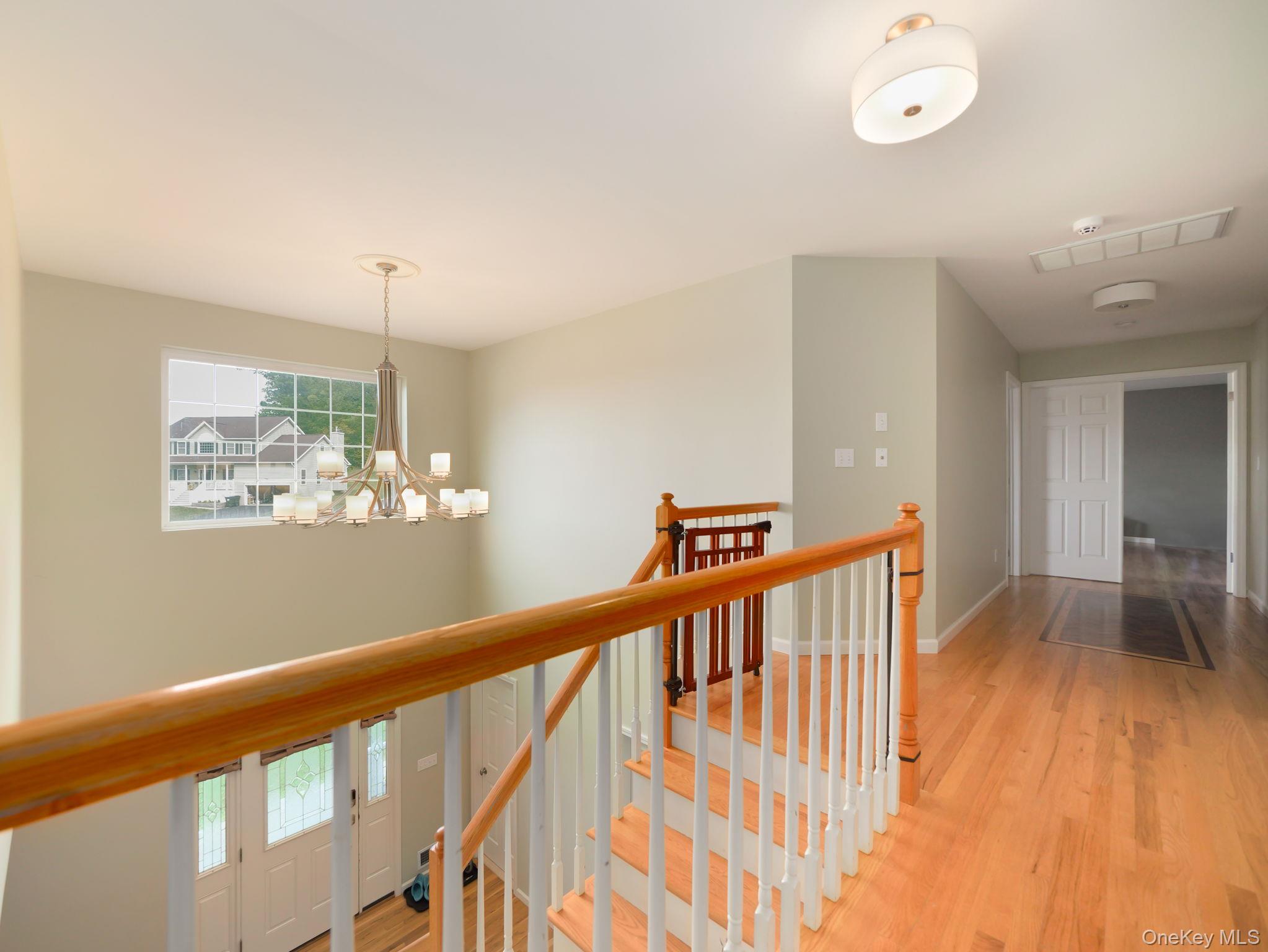 74 Red Maple Way New Windsor, NY 12553 - Photo 19 of 25 Corridor featuring light wood-type flooring, an upstairs landing, and a chandelier