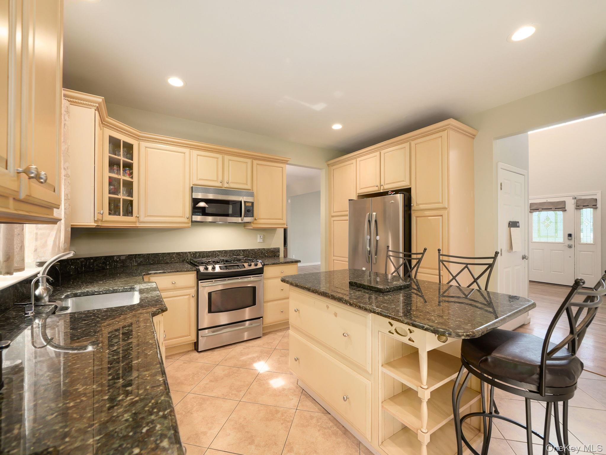74 Red Maple Way New Windsor, NY 12553 - Photo 5 of 25 Kitchen featuring a breakfast bar area, stainless steel appliances, dark stone countertops, recessed lighting, and light tile patterned floors