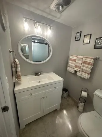 a bathroom with a sink mirror vanity and toilet