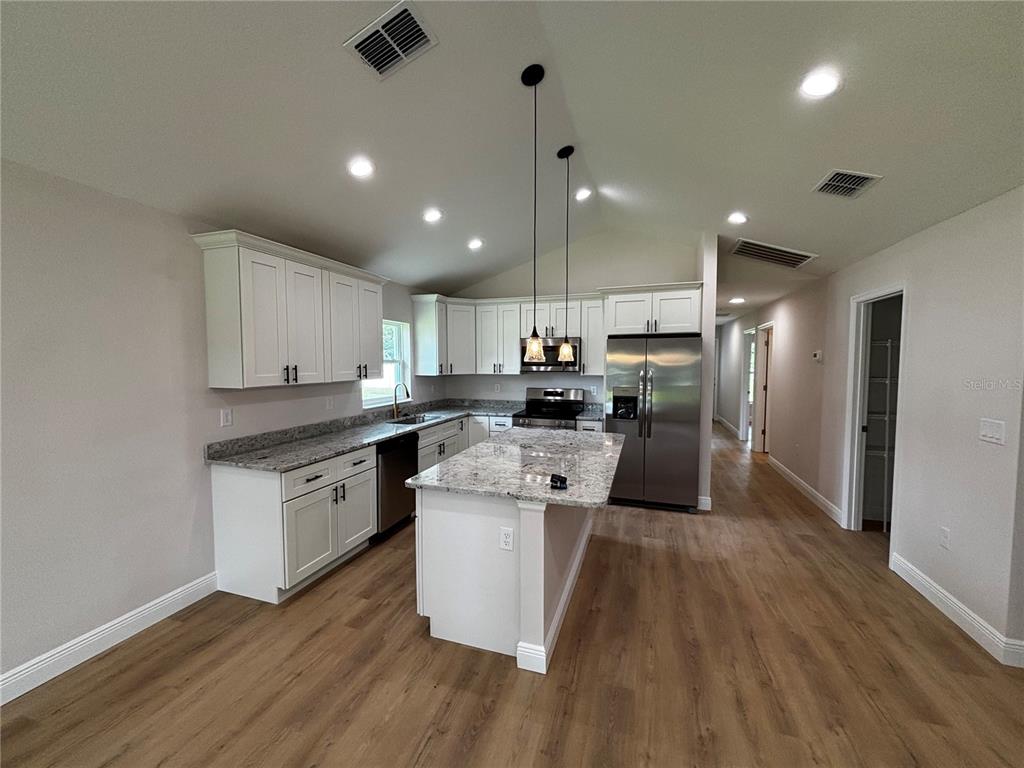 3148 Southwest 145th Court Ocala, FL 34481 - Photo 4 of 17 a kitchen with stainless steel appliances kitchen island granite countertop wooden floors and white cabinets