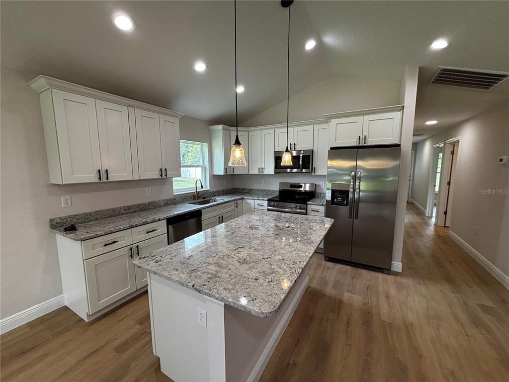 3148 Southwest 145th Court Ocala, FL 34481 - Photo 5 of 17 a kitchen with stainless steel appliances granite countertop a refrigerator a sink dishwasher a stove and white countertops with wooden floor