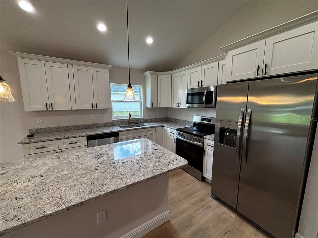 3148 Southwest 145th Court Ocala, FL 34481 - Photo 6 of 17 a kitchen with kitchen island granite countertop a refrigerator a sink a stove a microwave and island