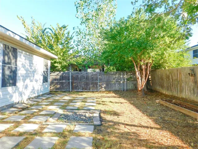 a view of a backyard with large tree and wooden fence