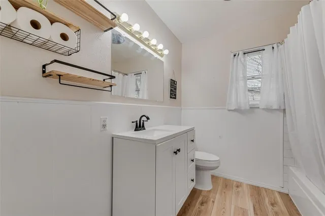 a bathroom with a sink a toilet a window and vanity