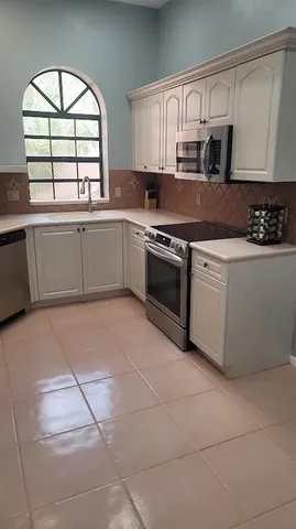 a kitchen with stainless steel appliances granite countertop a stove a sink and a white cabinets