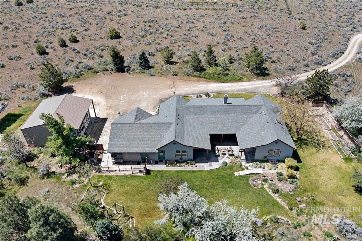 147 East Indian Crk Road Boise, ID 83716 - Photo 6 of 43 Spacious property featuring a large residence with a multi-gabled roofline, an expansive detached outbuilding, a manicured lawn, and a winding dirt road entry