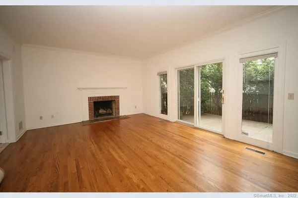 a view of empty room with floor to ceiling window and fireplace