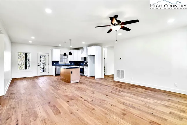 a large kitchen with stainless steel appliances a large center island and a wooden floor