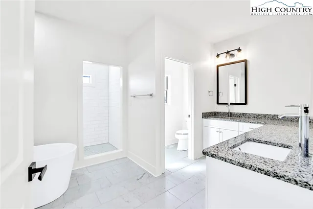 a bathroom with a granite countertop sink a toilet and shower