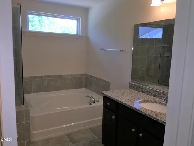 a bathroom with a granite countertop sink a mirror and a bathtub