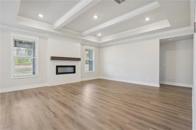 an empty room with wooden floor windows and cabinet