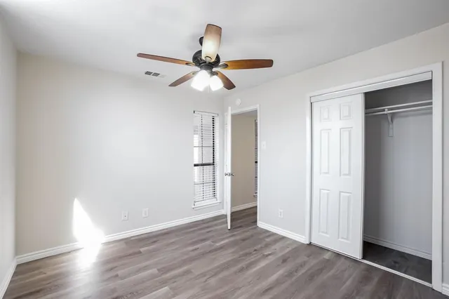 an empty room with wooden floor closet and windows