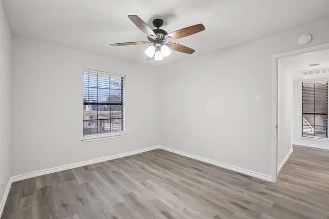 an empty room with wooden floor closet and windows