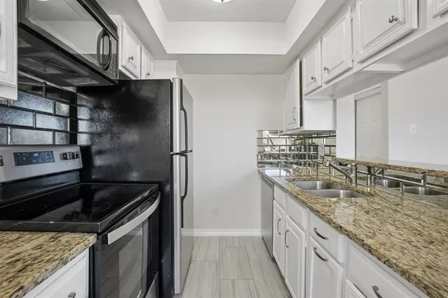 a kitchen with stainless steel appliances granite countertop a sink and a refrigerator