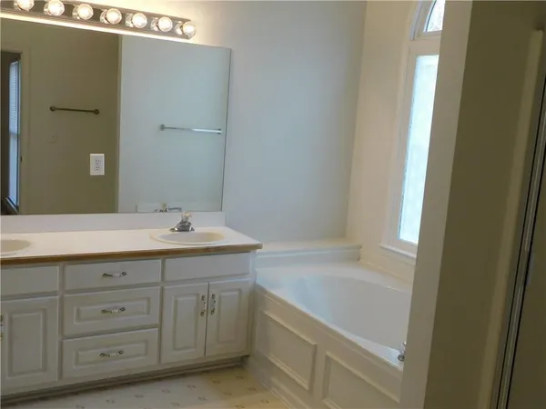 a bathroom with a tub sink and mirror