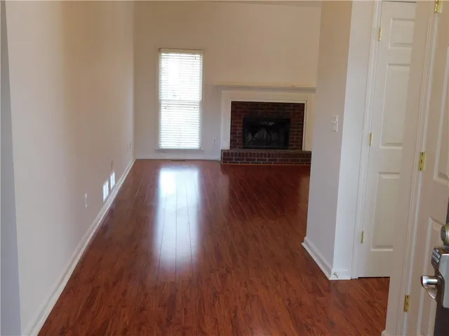 an empty room with wooden floor fireplace and windows